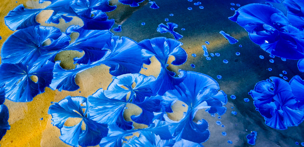 Blue floating floral shapes embedded in resin around a steel sphere.